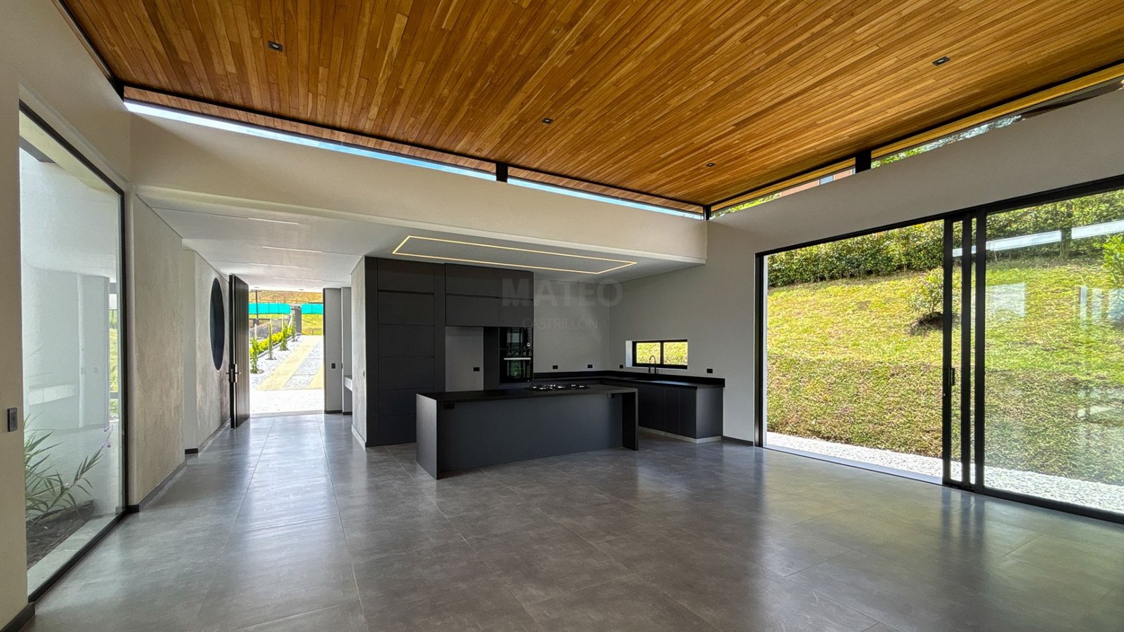 Cocina abierta con techo en madera y ventanales al jardín